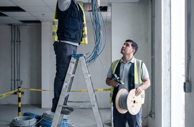 Dos tecnicos instalando cableado estructurado en el cielo falso de un edificio en obra